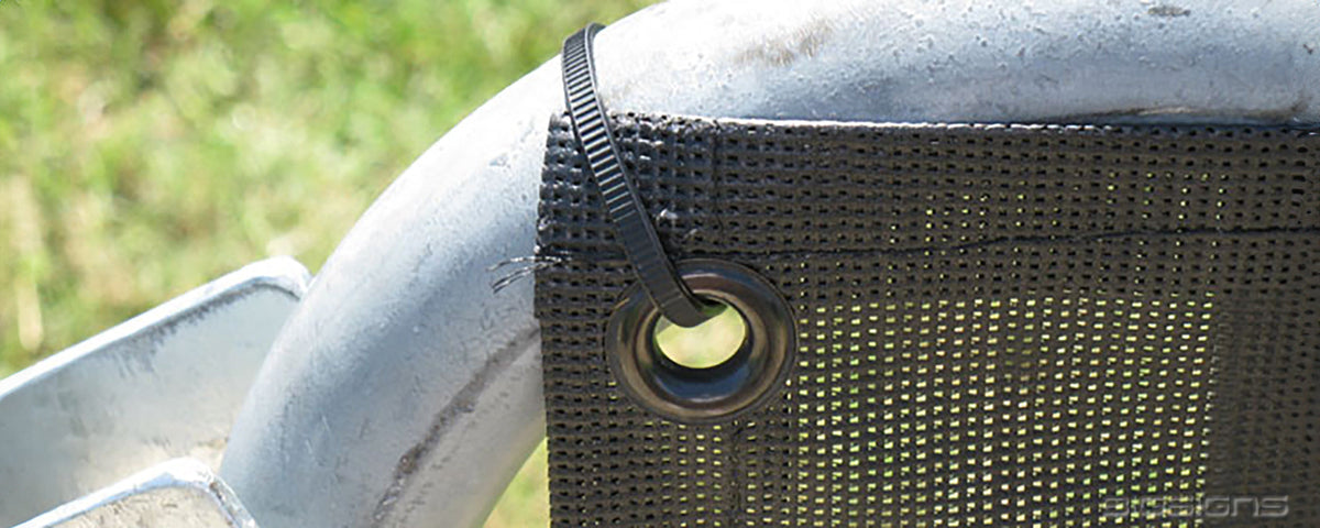 Close-up of a mesh barricade cover grommet zip-tied to a steel barricade rail