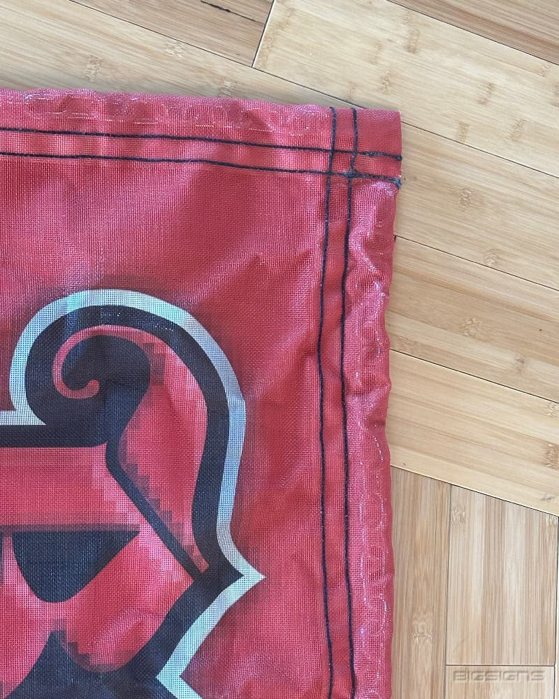 Close-up of a GatorMesh track protector corner with a printed logo and stitched hem