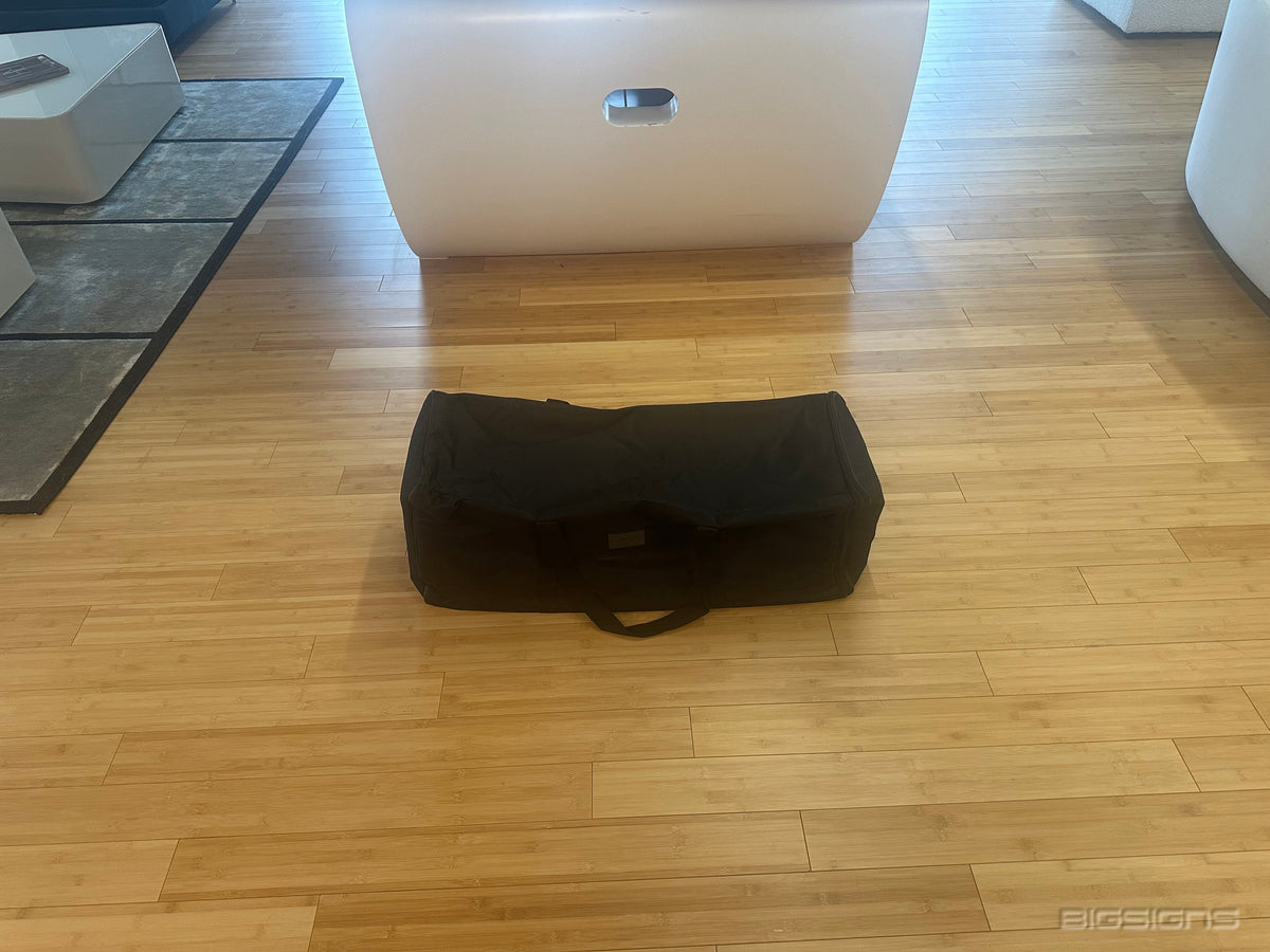 Black padded carrying bag for the pop-up backdrop on a wood floor