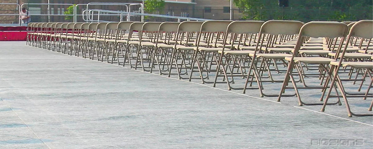 Rows of folding chairs set on a gray sideline blanket cover over turf