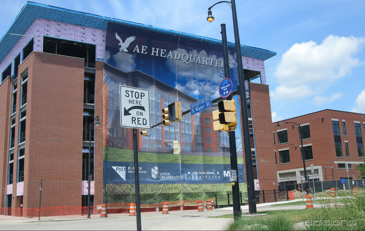 Large AE Headquarters vinyl banner covering the side of a brick building under construction