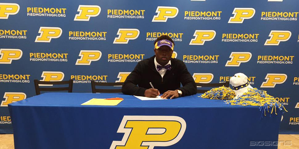 Student signing in front of a navy and gold Piedmont P logo backdrop and table cover