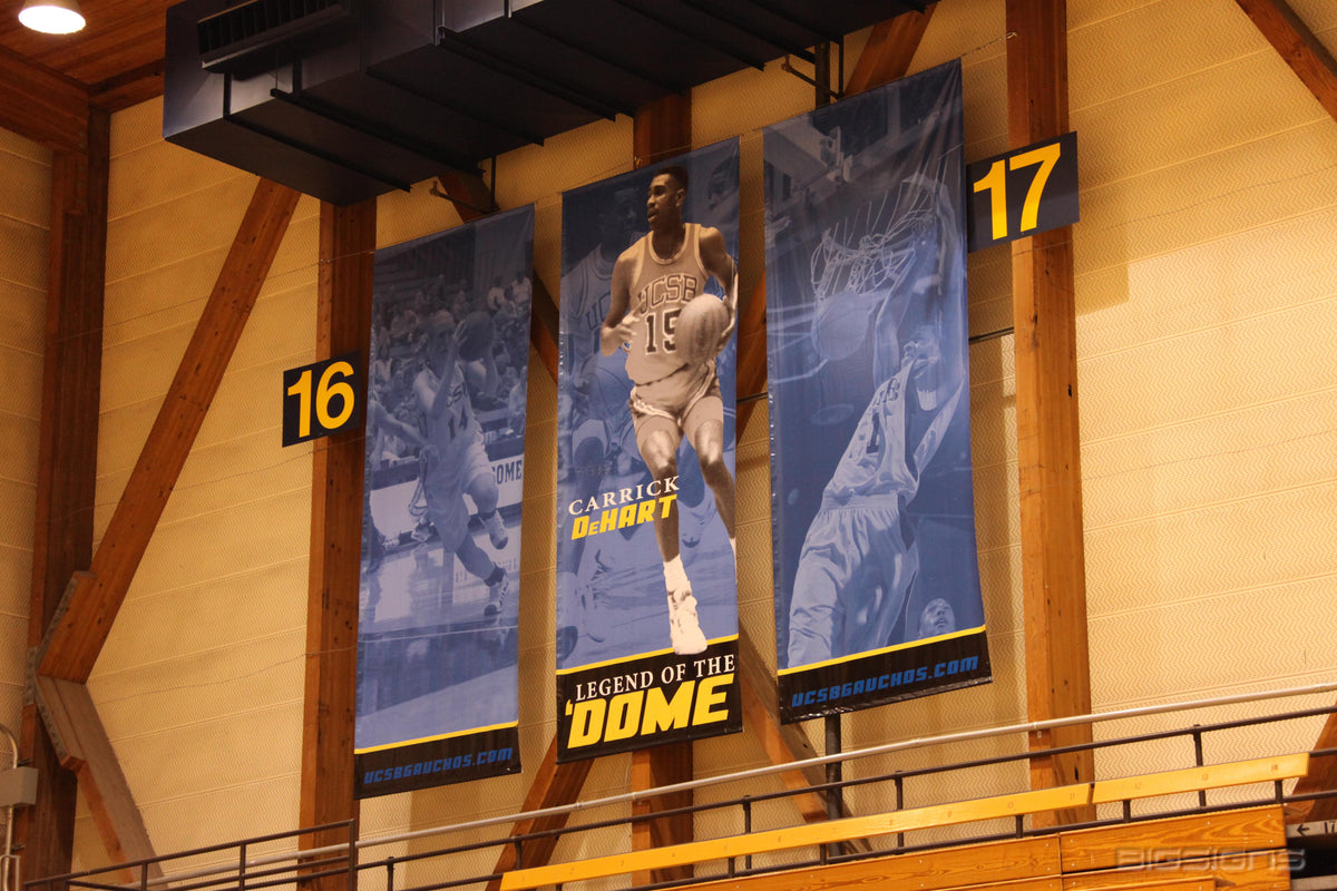 Legend of the Dome basketball player banners hanging between numbered posts in a fieldhouse