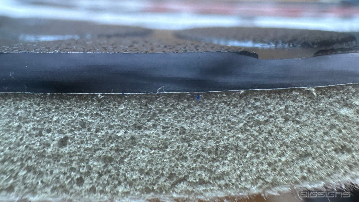 Close-up edge view of the on-deck circle's rubber top layer and foam backing