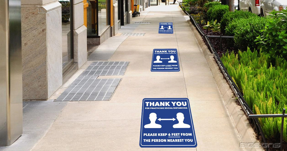 Blue Thank You for Practicing Social Distancing floor decals spaced along an outdoor sidewalk