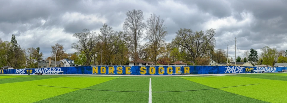 Blue printed athletic windscreen with bold team branding installed along a soccer field fence perimeter