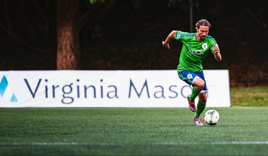 Athlete in motion beside a large branded sideline sign panel promoting a sponsor at the field's edge.