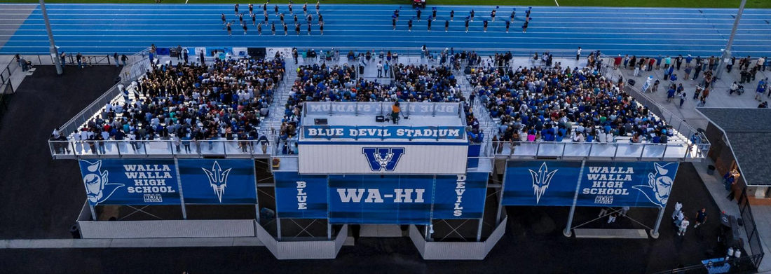 Wide view of a football stadium with stadium signage on press box and seats representing modern sports venue branding