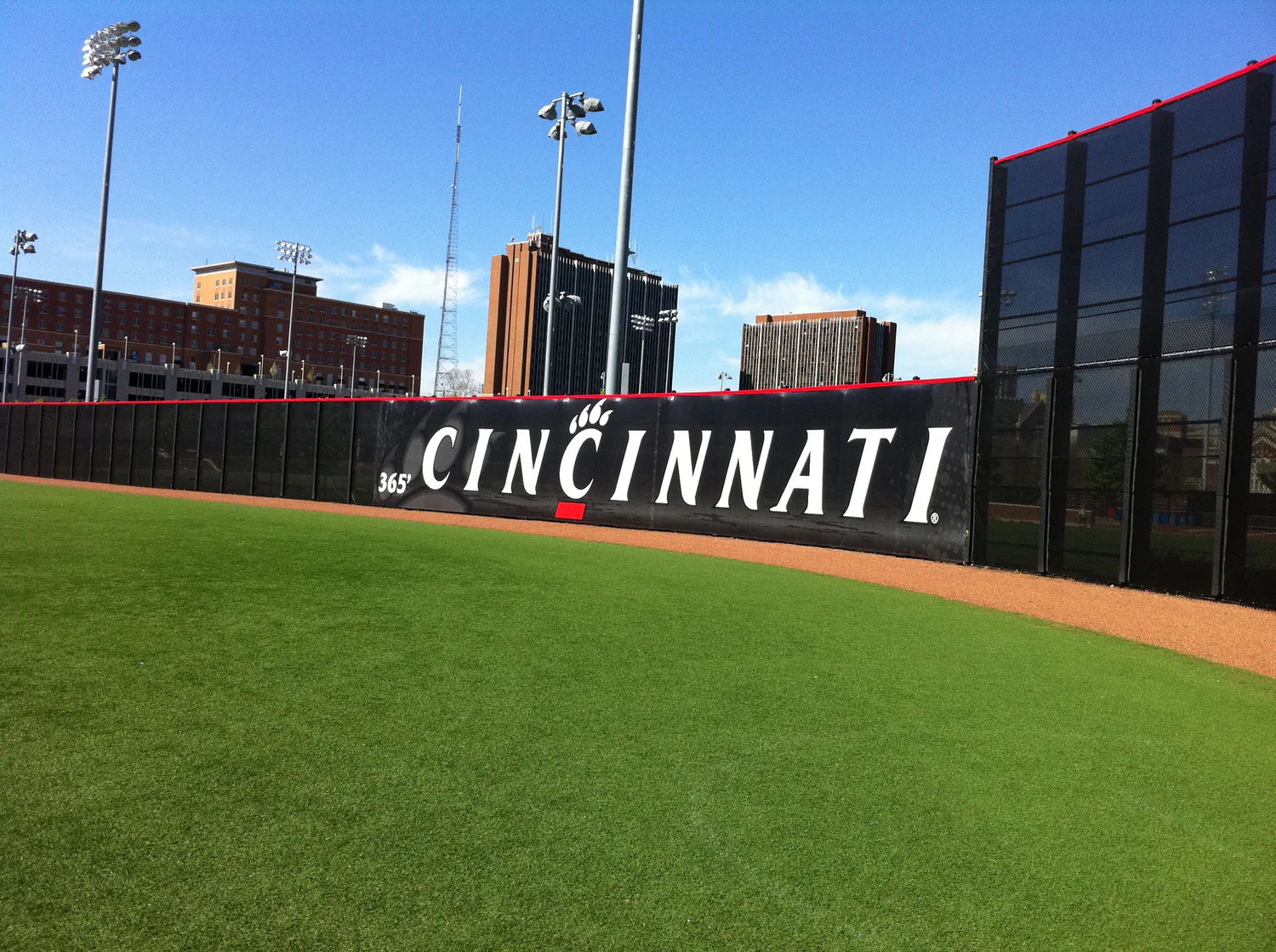 Custom baseball fence screen featuring a bold Cincinnati graphic installed along the outfield wall at a bright, open stadium.