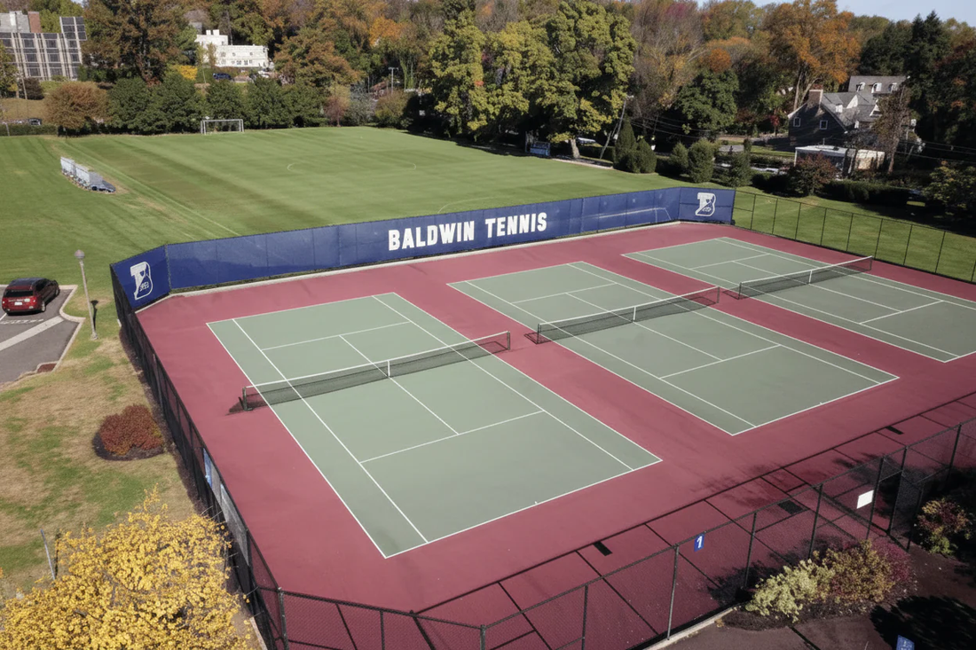 Tennis courts with custom tennis windscreen installed on fence for wind control, privacy, and strong facility branding