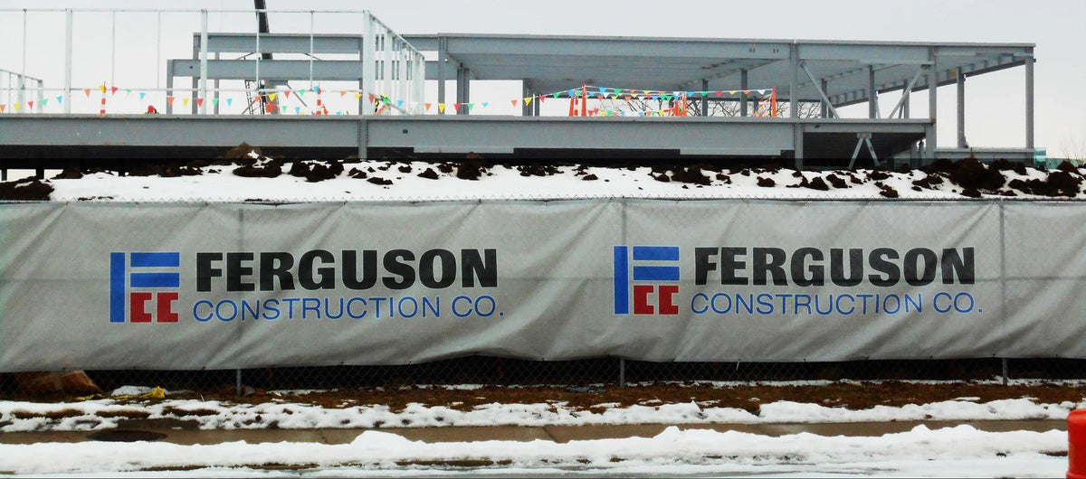 Construction fence graphics on chain link fencing showcasing contractor branding at active building site