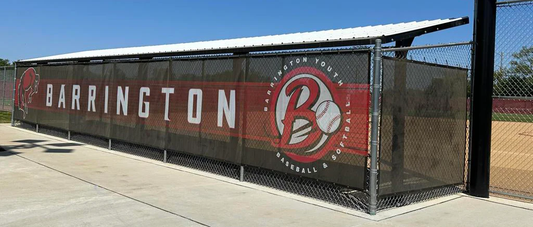 Custom dugout wraps installed on baseball field fence featuring Barrington team branding and bold graphics design