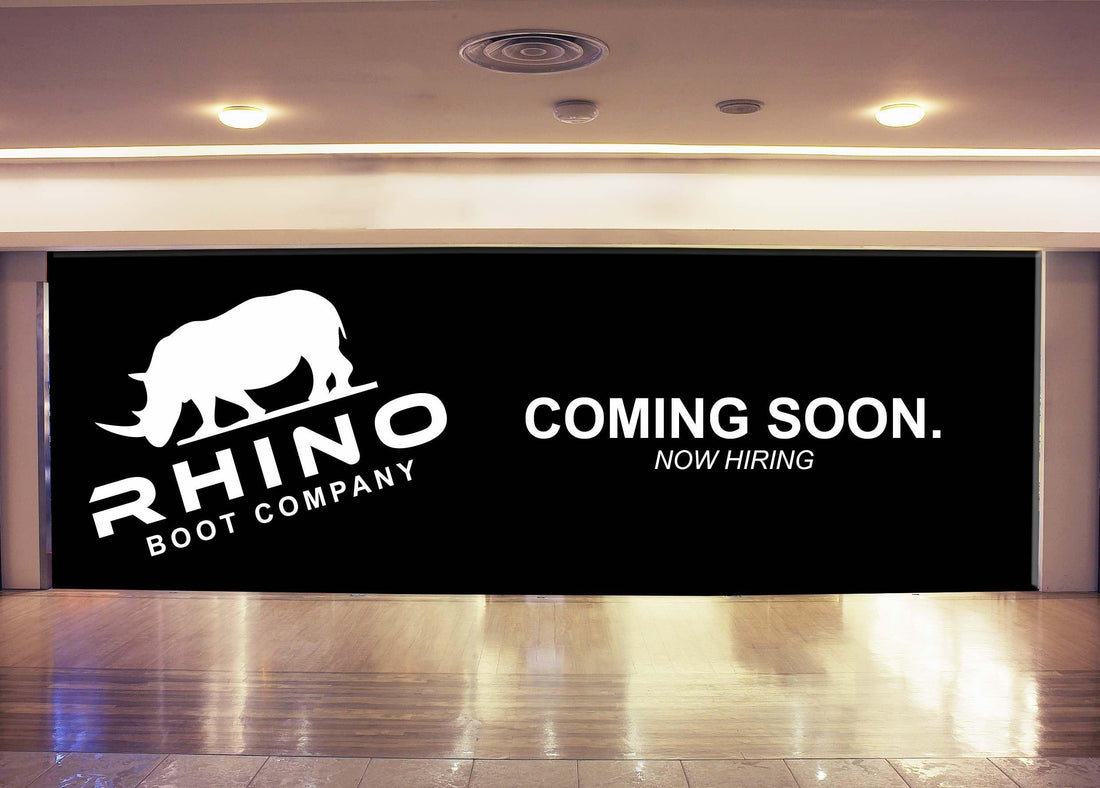 Retail construction barricade wall printed with a Coming Soon and Now Hiring message for Rhino Boot Company storefront