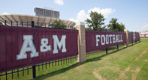 Athletic fence screen at football field providing wind control, privacy, and team branding from BigSigns.