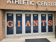 High-performance mesh windscreen featuring a custom full-color graphic of a stadium, mounted on a black chain-link fence.