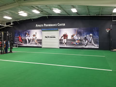 Modern gym with rows of custom power racks, inset lifting platforms, and bright LED lighting in a performance facility.