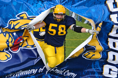 Football player bursting through a bulldog breakaway banner at a game