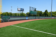 Dark green Chicago State University windscreen along a baseball outfield