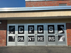 Custom mesh windscreen on a school fence featuring a large "Crown Point Panthers" logo and purple and white branding.