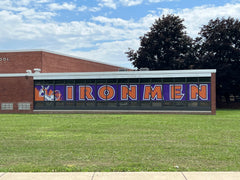 Custom mesh windscreen on a tennis court fence featuring Danville High School branding and "Home of the Admirals" text.