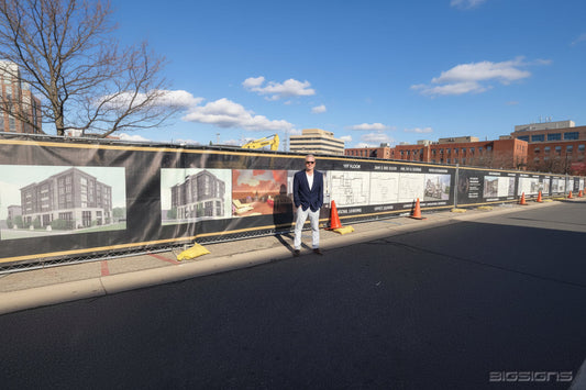 Man standing in front of a long building rendering vinyl mesh screen on a fence