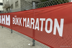 Red Bukk Maraton fabric mesh banner stretched along a fence
