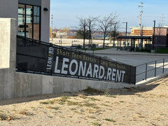 Custom athletic windscreen with bold graphics on chain-link fence at sports facility, ideal for fields, gyms, and events.