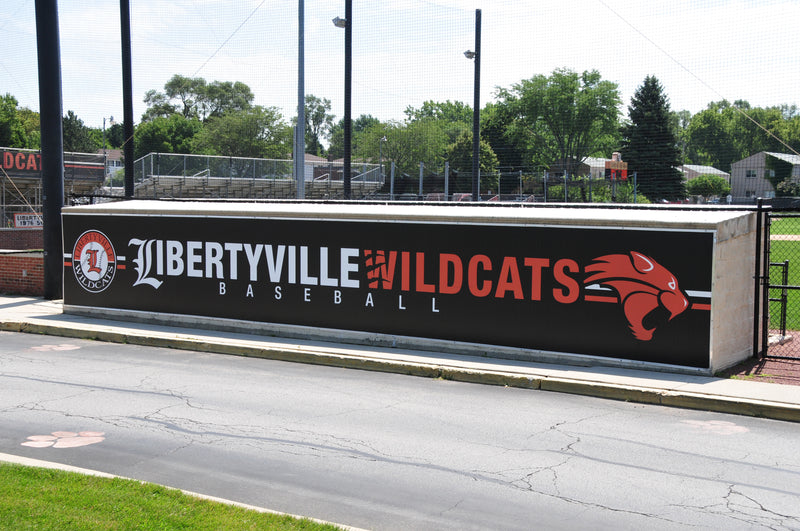 Long black dugout wrap reading Libertyville Wildcats Baseball with a red wildcat logo