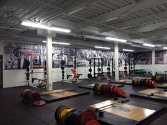 Minot State training facility with red and black equipment, synthetic turf flooring, and large team branding graphics.