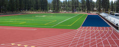 Blue track protector covering a running track corner at a turf field