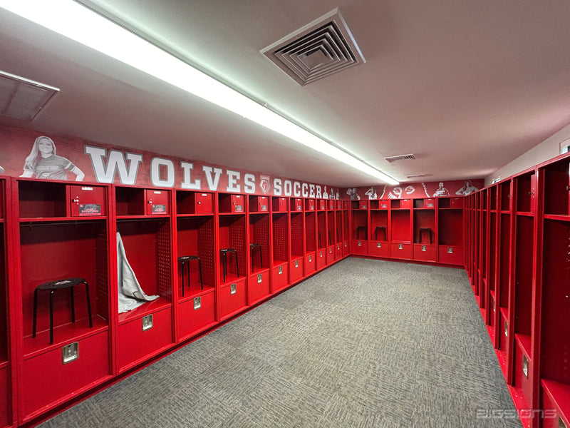 Long locker room lined with lockers under a header graphic reading Wolves Soccer