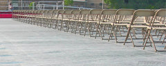 Rows of folding chairs set on a gray sideline blanket cover over turf