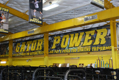 High school gym with gold and black branding, custom-wrapped pillars, and motivational wall graphics for athlete training.