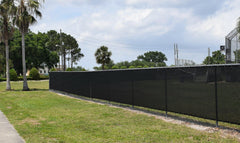 Black extreme windscreen stretched on chain-link fence at sport field, illustrating heavy-duty outdoor wind and privacy screen.