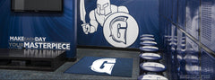 Navy G logo floor mat in front of lockers in a Spartan-themed locker room