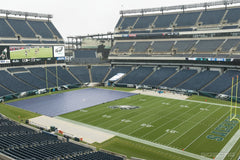 Gray FieldCover™ tarp partly covering a stadium football field beside the Eagles end zone