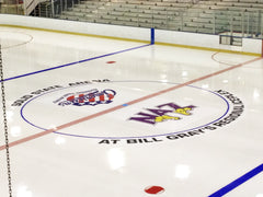 Custom center ice logo at Bill Gray's Regional Iceplex featuring NA initials and circular arena text on bright white ice.
