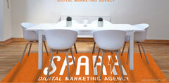 Orange Spark Digital Marketing Agency logo rug under a white meeting table