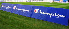Windscreens attached to fence around field on grass, illustrating durable wind blockage and outdoor site screening.