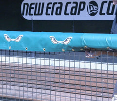 Rail padding with printed team logos & sponsor graphics attached to stadium fencing for player safety and professional look.